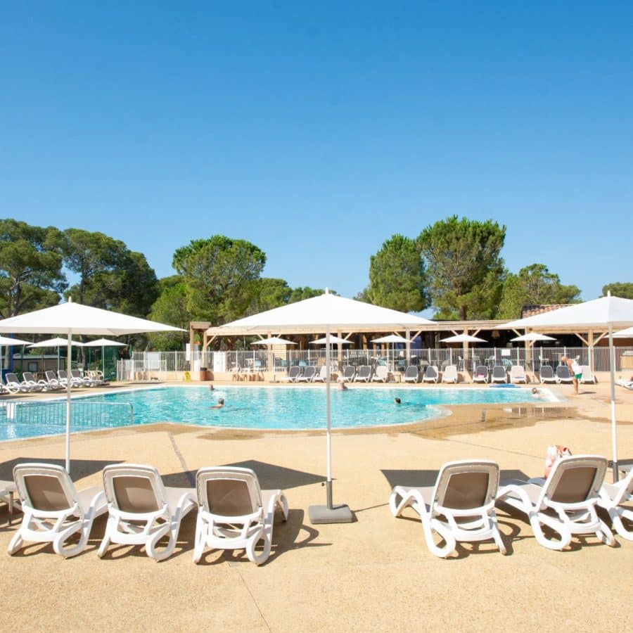 Transats et parasols autour de la piscine du camping dans le Var.